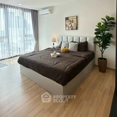 Spacious modern bedroom with city view, featuring elegant decor and natural light.