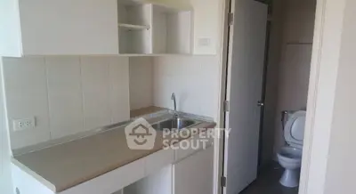 Compact kitchen area with adjacent bathroom in modern apartment