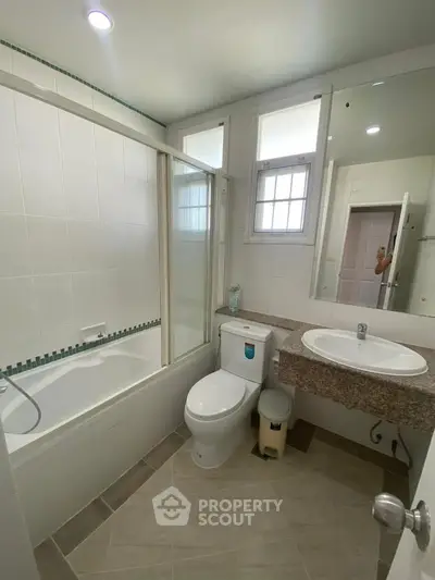 Modern bathroom with bathtub and sleek fixtures in a bright, tiled setting.