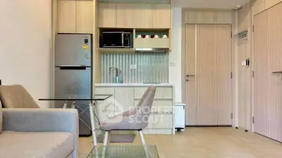Modern compact kitchen with integrated appliances and cozy seating area in stylish apartment.