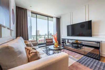 Luxurious living room with modern decor and city view, featuring a large TV and comfortable seating.