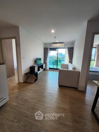 Modern living room with wooden flooring and balcony view in a stylish apartment.