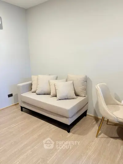 Modern living room with cozy beige sofa and elegant chair on wooden flooring.