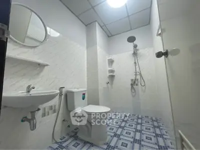 Modern bathroom with shower, toilet, and sink in a tiled setting.