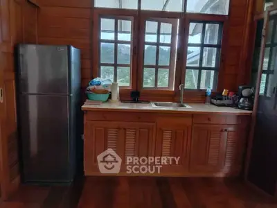 Charming rustic kitchen with wooden cabinetry and large windows offering scenic views.