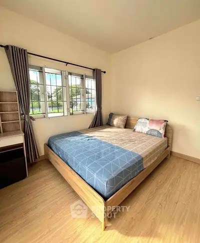 Cozy bedroom with large window and stylish decor, perfect for relaxation and comfort.