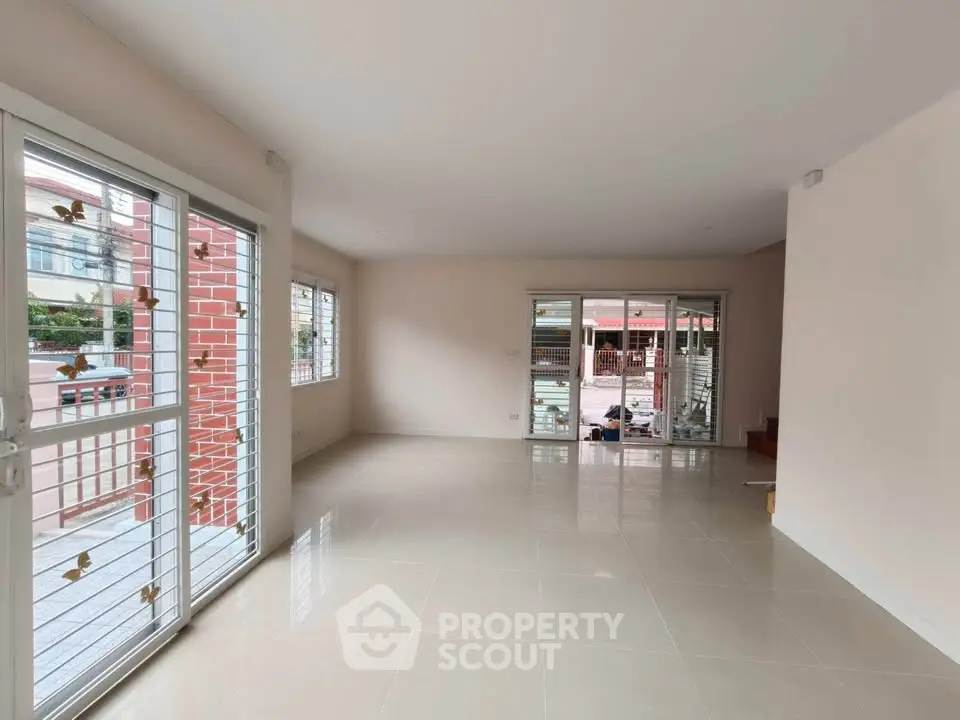 Spacious empty living room with large windows and tiled floor, perfect for customization.