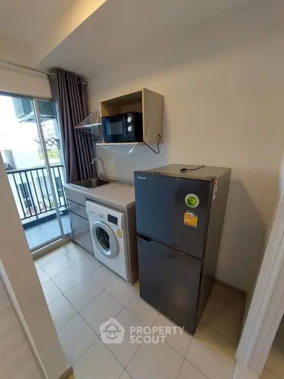 Modern kitchen with appliances and balcony view in a compact apartment