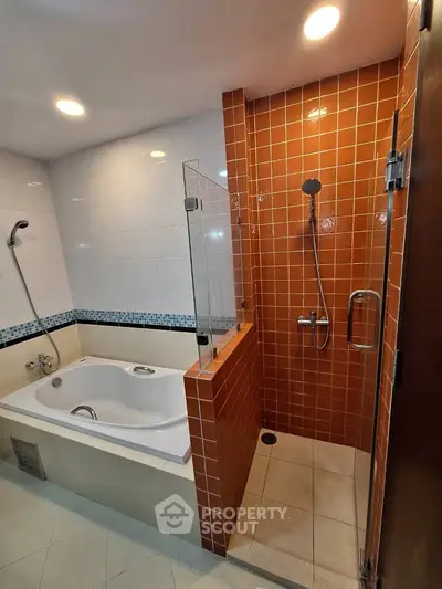 Modern bathroom with bathtub and glass-enclosed shower in stylish real estate property.