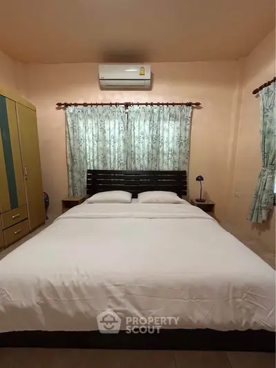 Cozy bedroom with air conditioning and elegant curtains, perfect for a restful night's sleep.