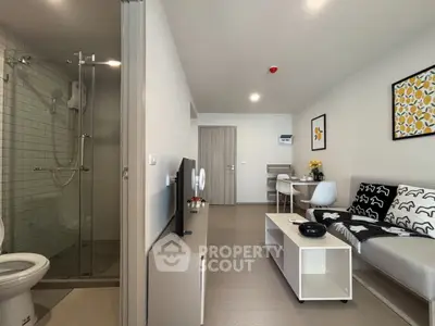 Modern studio apartment with sleek living area and glass-enclosed shower, ideal for urban living.