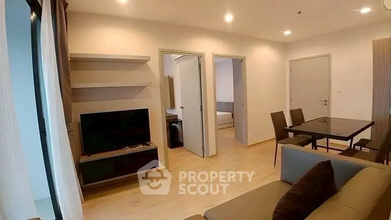 Modern living room with open layout and dining area, featuring sleek furniture and neutral tones.