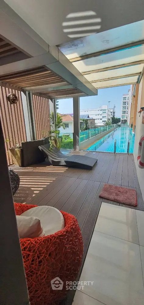 Luxurious poolside lounge area with modern wicker furniture and sleek wooden decking, offering a serene urban oasis amidst a bustling cityscape.