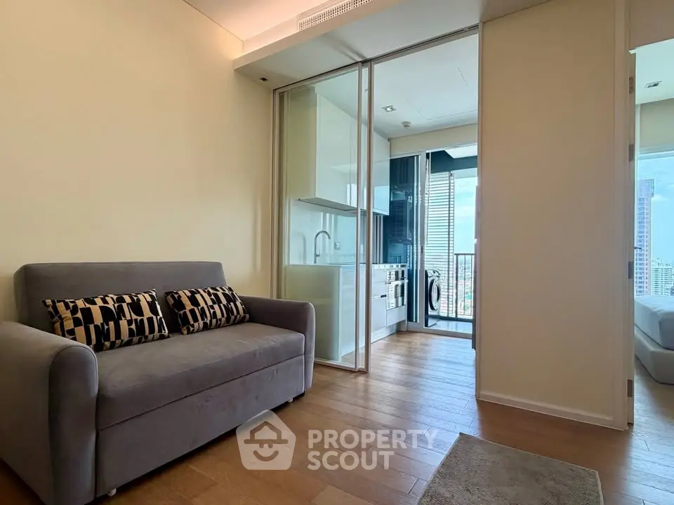 Modern apartment interior with cozy living room and sleek kitchen leading to a balcony with city views.