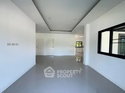 Spacious modern living room with sleek white tiles and large windows for natural light.