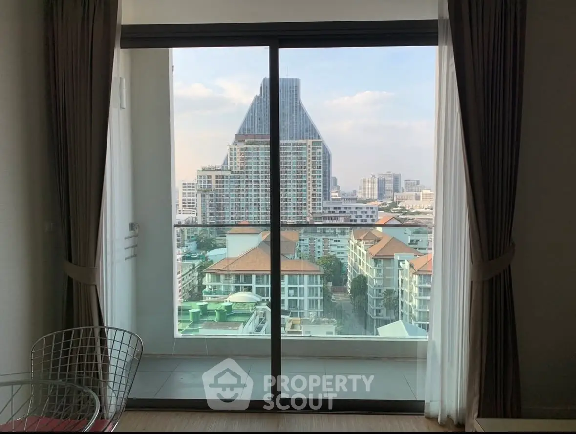 Stunning city view from modern apartment balcony with floor-to-ceiling glass doors.