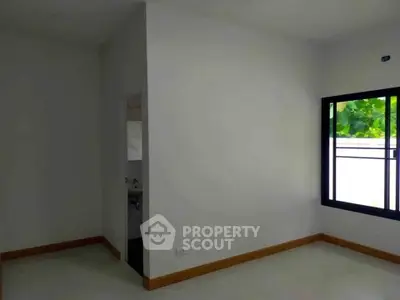 Bright empty room with large window and white walls, perfect for customization.