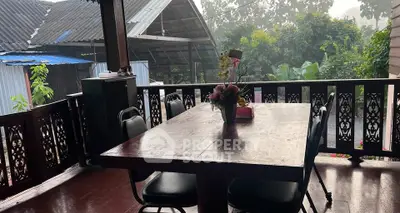 Charming rustic balcony with wooden table and lush garden view, perfect for serene outdoor dining.