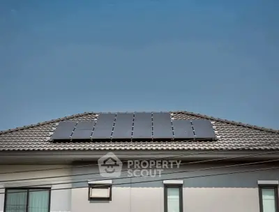 Modern house with solar panels on the roof under clear blue sky.