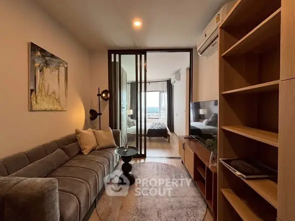 Modern living room with stylish decor and cozy ambiance, featuring a view into a chic bedroom.