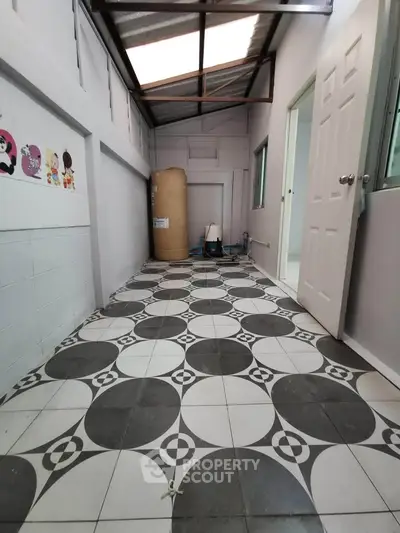 Spacious utility area with patterned tile flooring and ample natural light, perfect for storage or laundry setup.