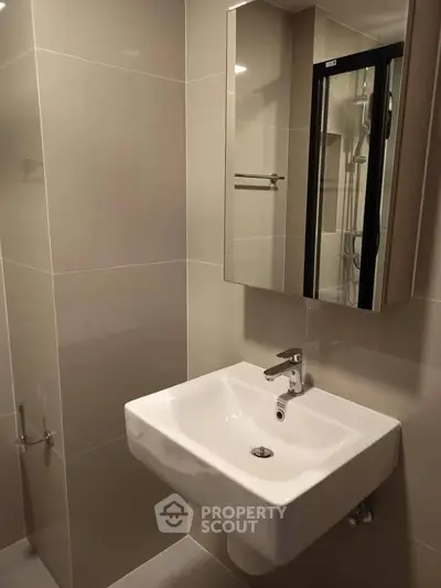 Modern bathroom with sleek sink and mirrored cabinet in a contemporary apartment.