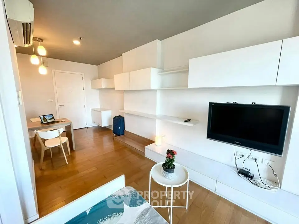 Modern living room with sleek white shelving and mounted TV, featuring wooden flooring and ambient lighting.