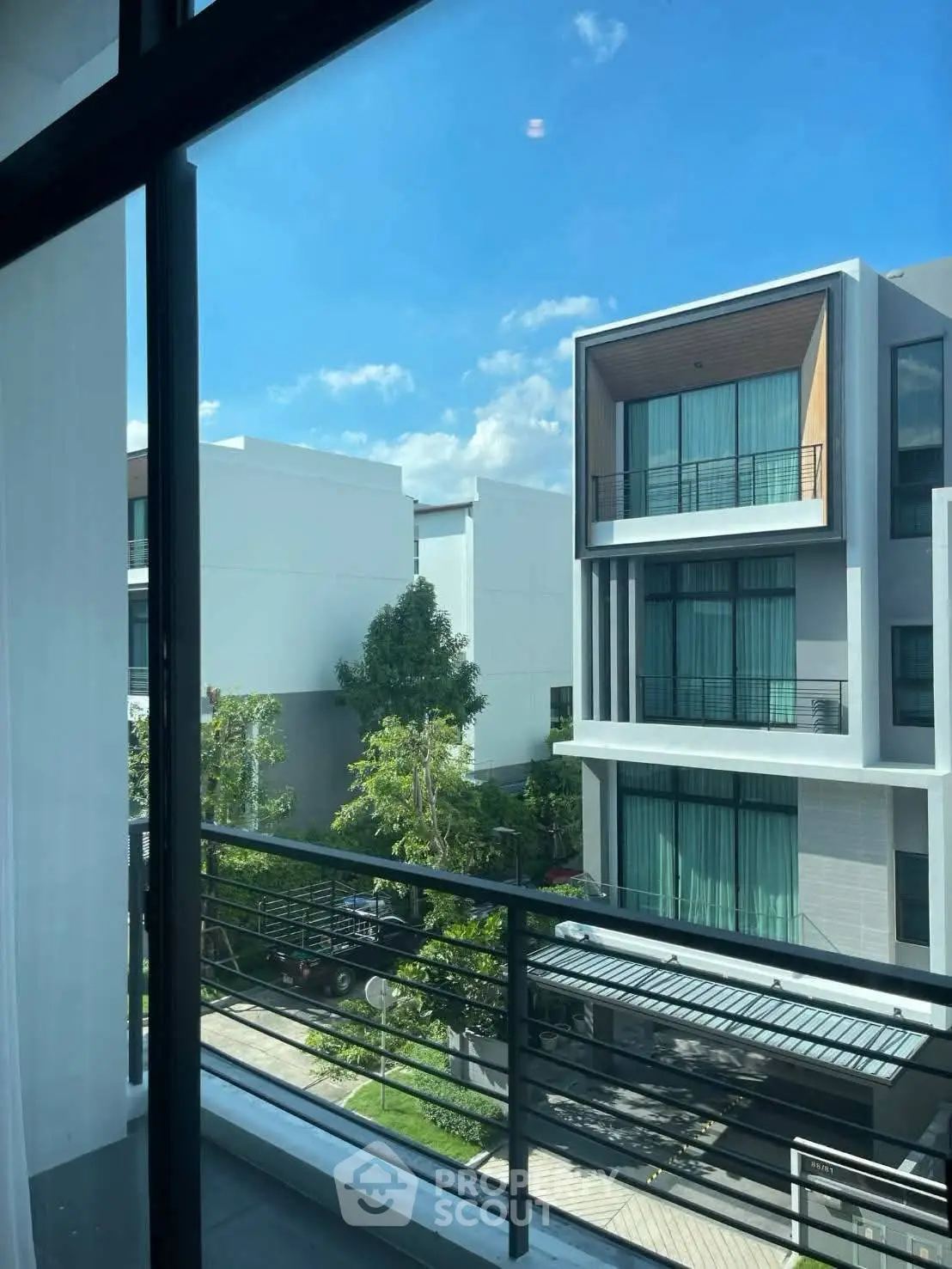 Modern residential building with balconies and large windows under a clear blue sky.