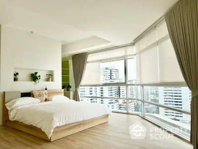 Spacious bedroom with large windows offering stunning city views and modern decor.