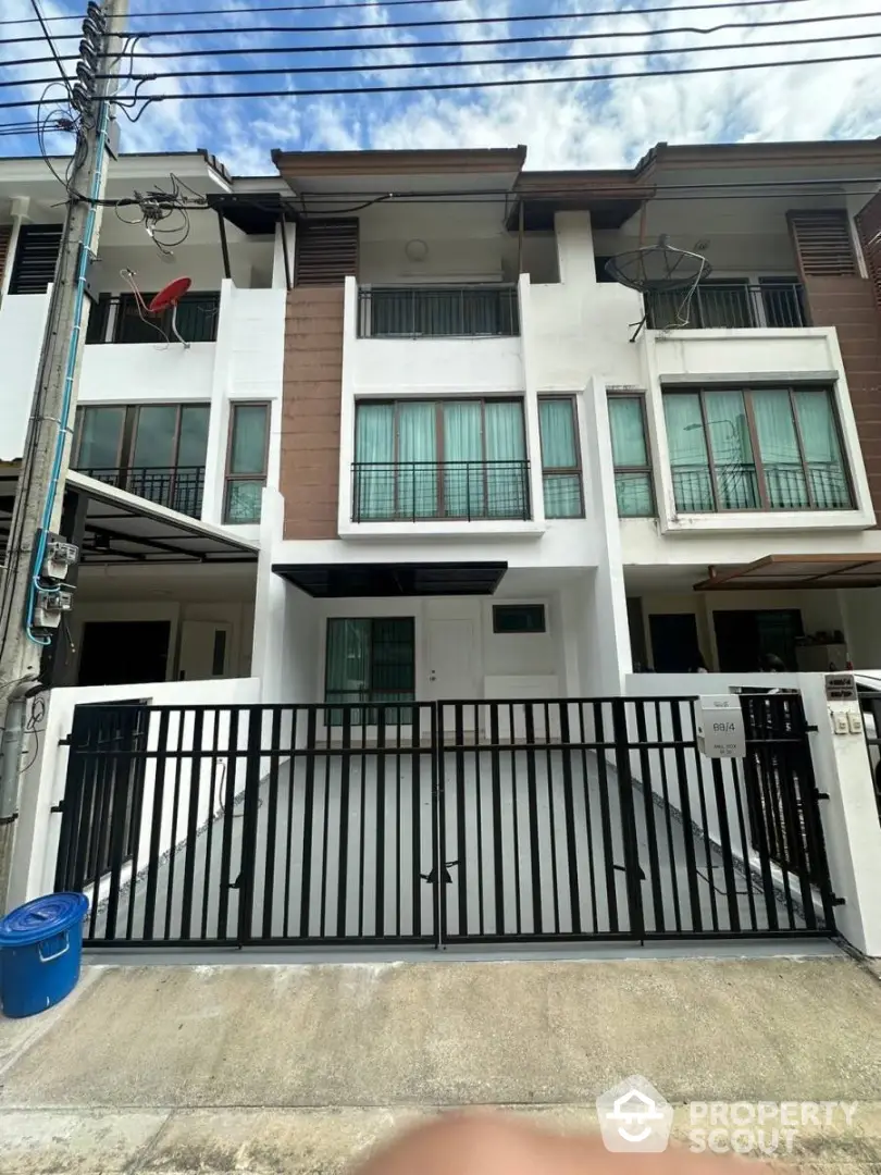 Modern townhouse exterior with gated driveway and balcony, ideal urban living space.