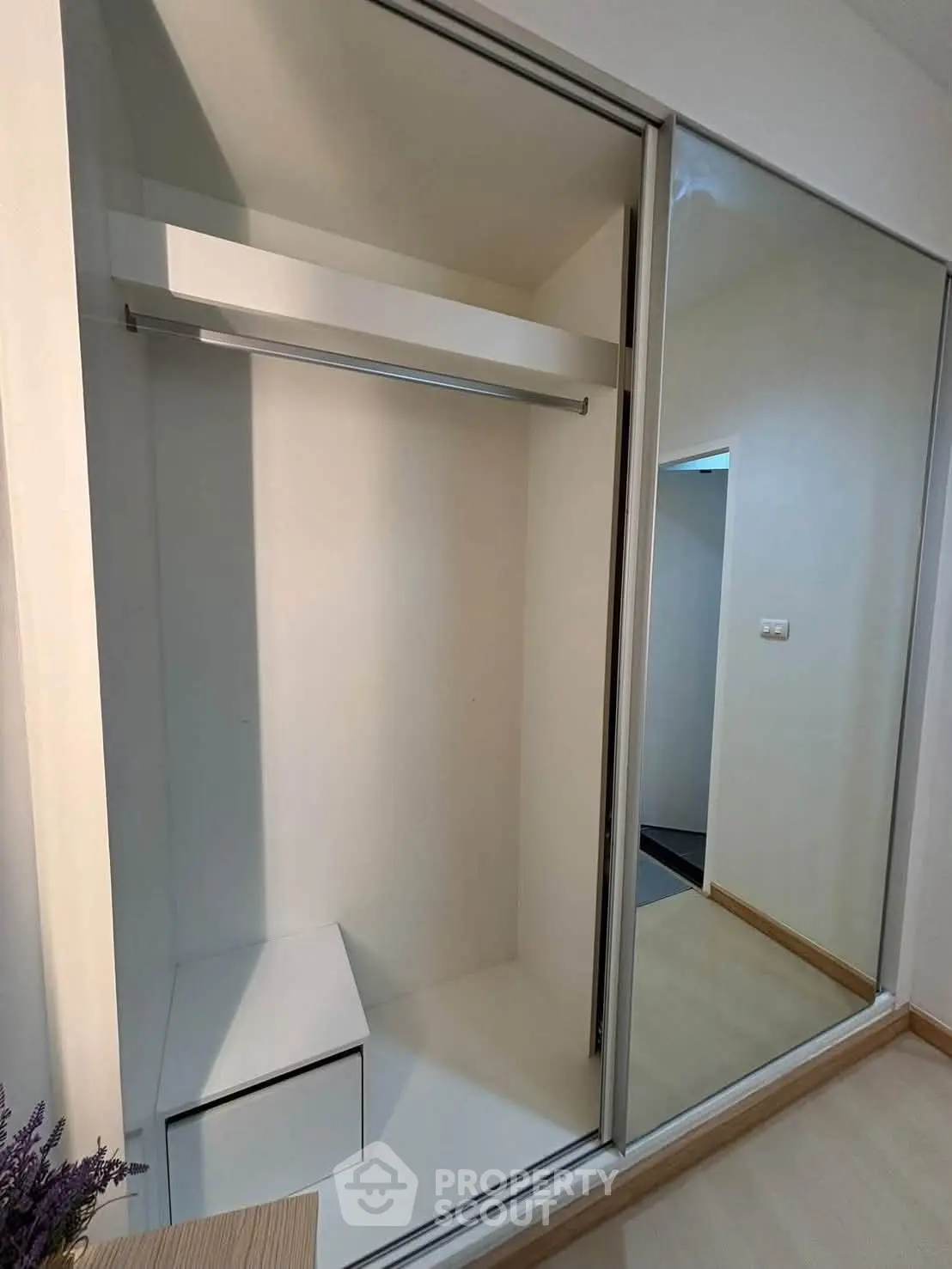 Spacious built-in wardrobe with sliding mirrored doors in modern apartment.