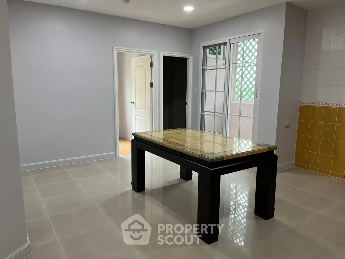 Spacious dining area with elegant table and access to balcony in modern apartment.