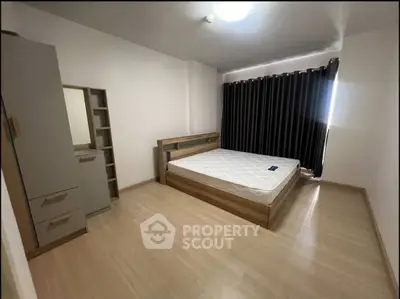 Spacious bedroom with modern wooden furniture and large window with blackout curtains.
