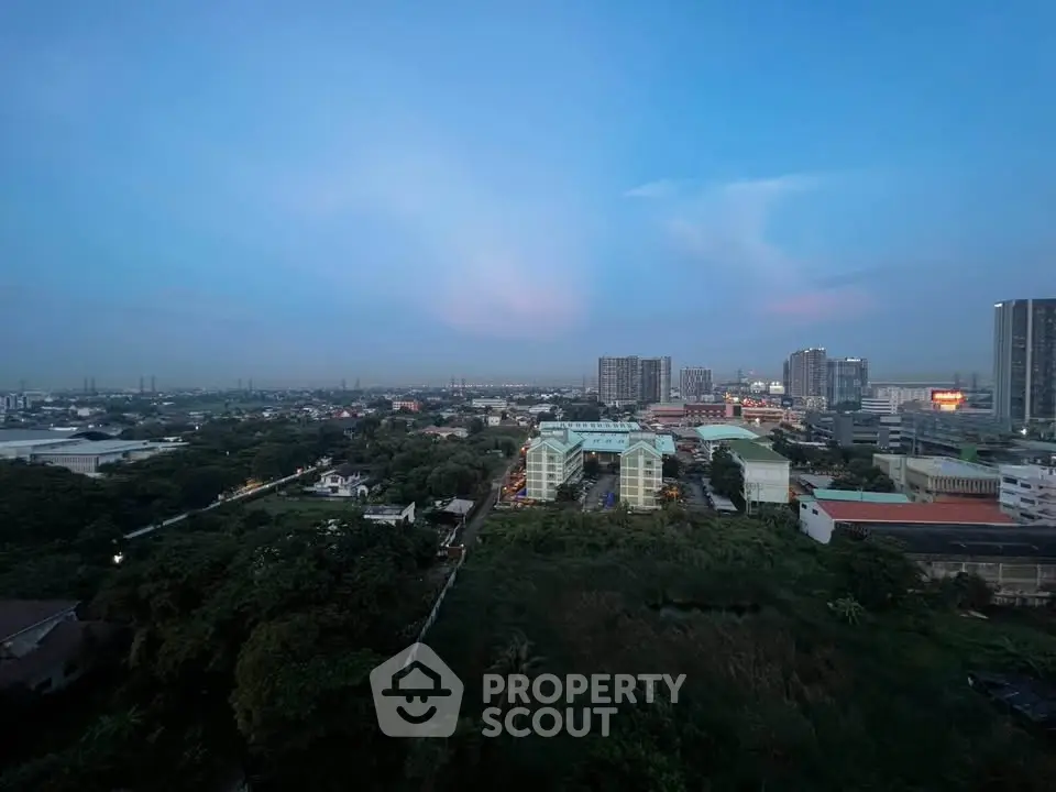 Stunning cityscape view from high-rise building at dusk, showcasing urban skyline and lush greenery.