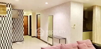 Modern living room with stylish decor and open layout, featuring geometric wall patterns and sleek furniture.