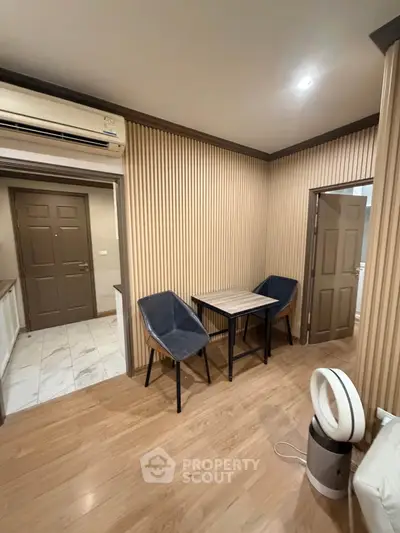 Modern interior with wooden flooring, stylish chairs, and air conditioning in a cozy living space.