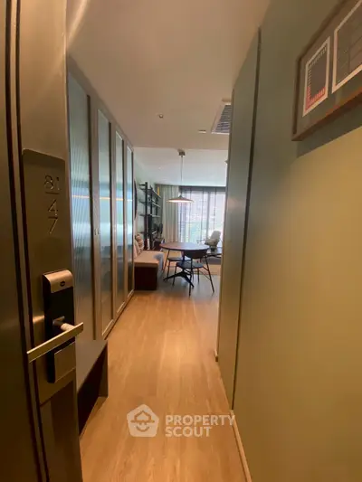 Modern apartment entrance leading to a stylish living room with wooden flooring and contemporary decor.
