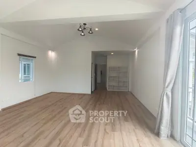 Spacious empty room with wooden flooring and modern lighting, perfect for customization.