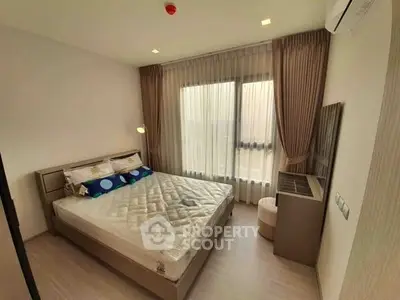 Modern bedroom with large window and stylish decor in a contemporary apartment.
