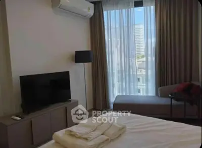 Modern bedroom with city view, featuring a TV, air conditioning, and stylish decor.