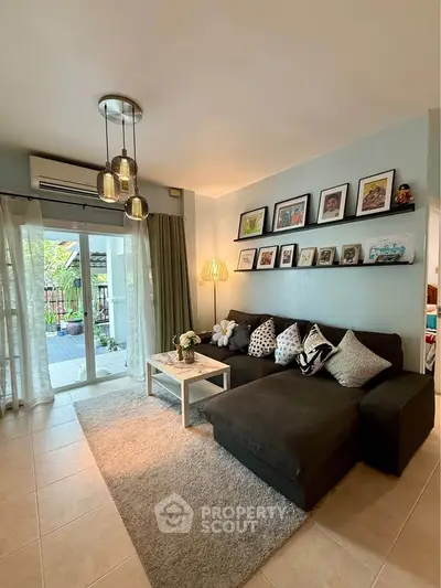 Charming living room with cozy sectional sofa and gallery wall, opening to a lush balcony view.