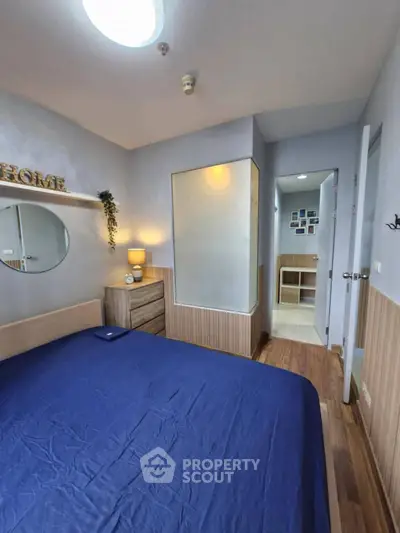 Cozy bedroom with modern decor and wooden flooring, featuring a stylish dresser and soft lighting.
