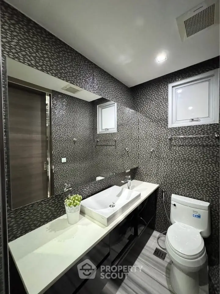 Modern bathroom with sleek design, featuring a stylish sink and toilet, perfect for contemporary living.