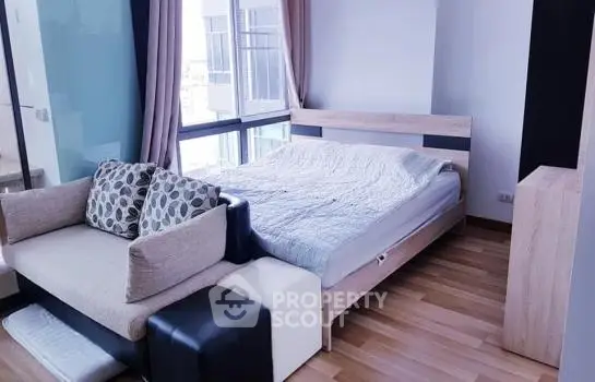 Modern bedroom with large windows and cozy seating area in a stylish apartment.