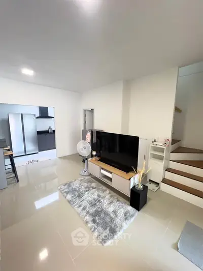 Modern living room with sleek TV setup and open kitchen layout, perfect for contemporary living.