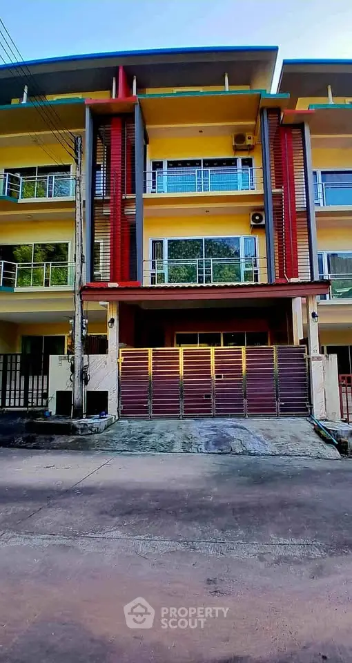 Modern multi-story building with vibrant facade and gated entrance, ideal for urban living.