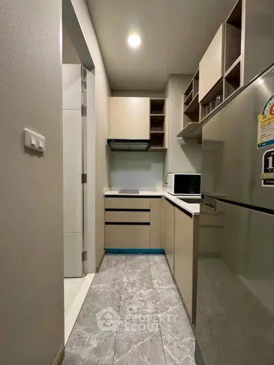 Modern compact kitchen with sleek cabinetry and stainless steel appliances in a cozy apartment.