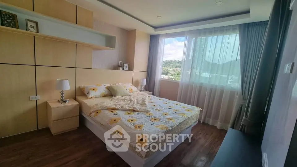 Spacious bedroom with large window offering scenic views, featuring modern decor and wooden flooring.