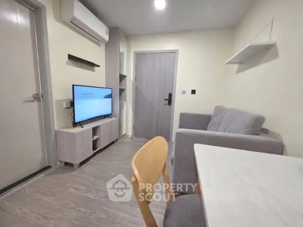 Modern living room with sleek furniture and wall-mounted TV in a cozy apartment.