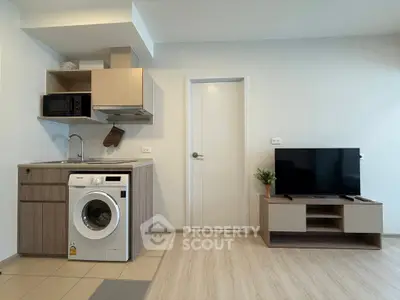 Modern studio apartment with compact kitchen and washing machine, ideal for urban living.